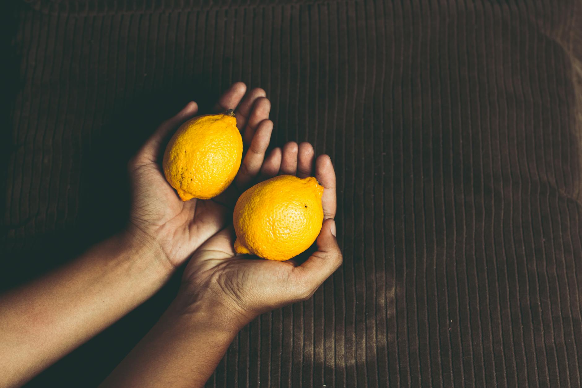 Two fresh lemons held in cupped hands, symbolizing gentle, natural intimacy